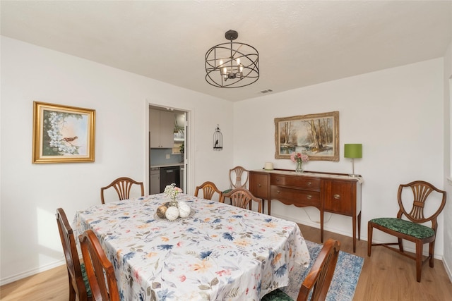 dining space with light wood-type flooring and a chandelier