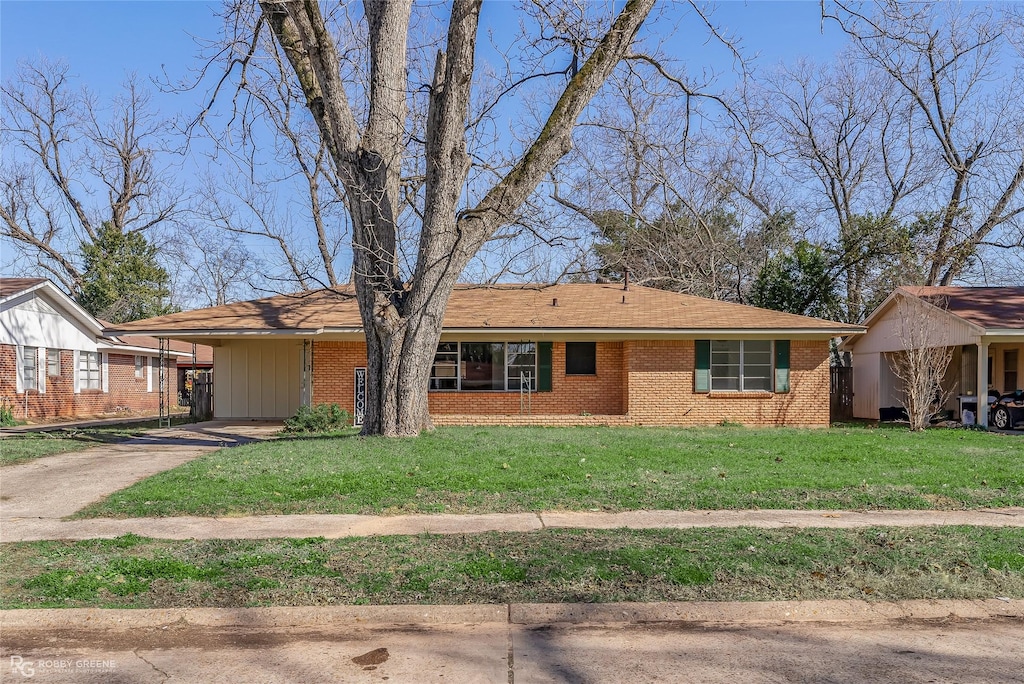 ranch-style home featuring a carport and a front lawn