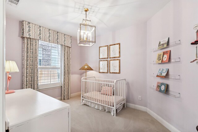 bedroom with light colored carpet, a nursery area, and an inviting chandelier