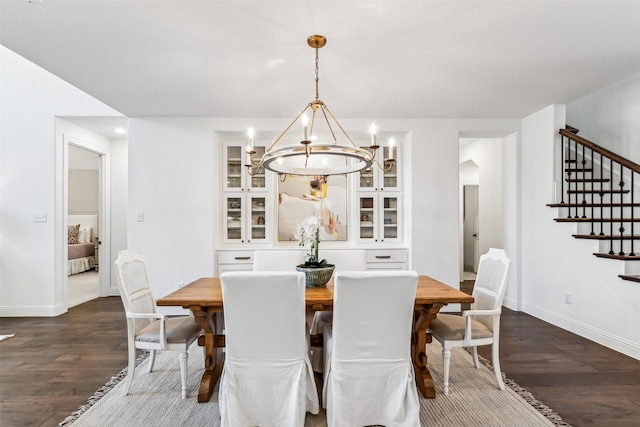 dining space featuring baseboards, arched walkways, dark wood-style floors, stairs, and a chandelier