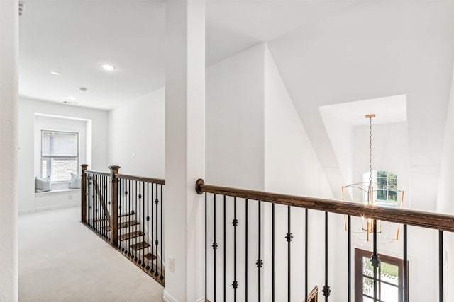 corridor featuring an inviting chandelier and carpet floors