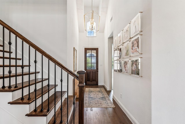 foyer entrance with baseboards, stairway, dark wood-type flooring, an inviting chandelier, and a high ceiling