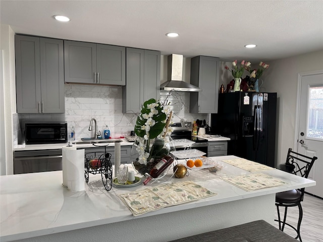 kitchen featuring black appliances, wall chimney range hood, sink, backsplash, and gray cabinets