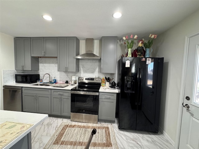 kitchen featuring black appliances, wall chimney exhaust hood, gray cabinetry, and sink