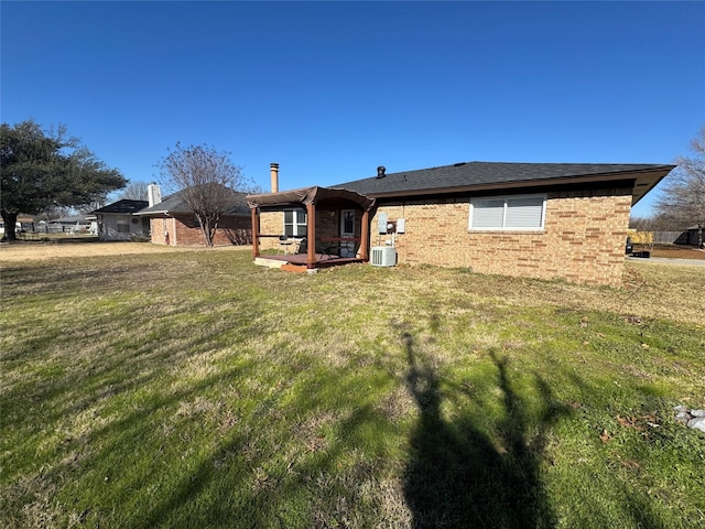 rear view of property featuring a lawn and central AC