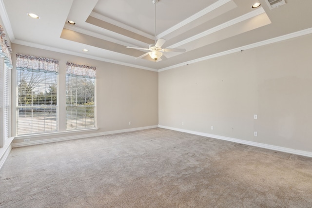 unfurnished room with a raised ceiling, crown molding, and carpet flooring