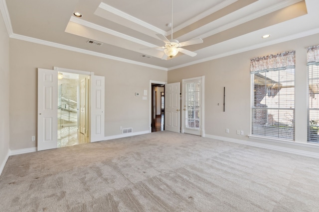 carpeted empty room with a tray ceiling and ornamental molding