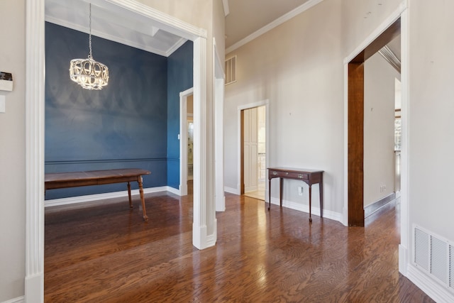 interior space with a towering ceiling, a chandelier, ornamental molding, and dark hardwood / wood-style flooring