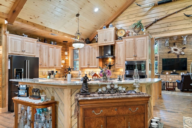 kitchen with wall chimney range hood, a center island with sink, light hardwood / wood-style flooring, and hanging light fixtures