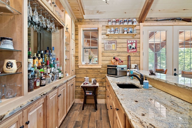 bar featuring sink, beam ceiling, light stone counters, dark hardwood / wood-style floors, and wooden walls