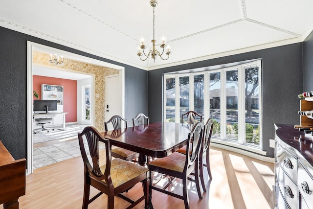 dining area featuring ornamental molding, an inviting chandelier, light hardwood / wood-style floors, and lofted ceiling