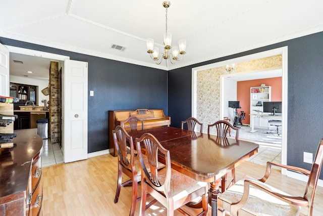 dining area featuring light wood-type flooring, a chandelier, and ornamental molding