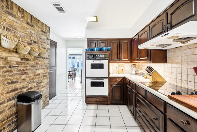 kitchen with light tile patterned floors, black electric stovetop, double oven, and dark brown cabinetry