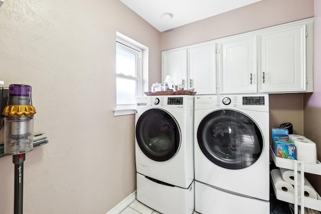 laundry room with separate washer and dryer, light tile patterned floors, and cabinets