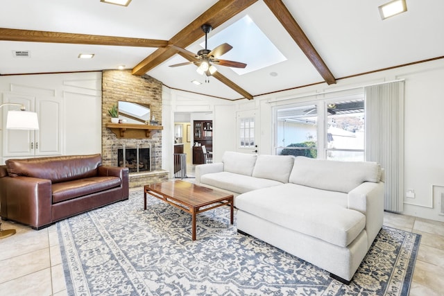 tiled living room featuring ceiling fan, a fireplace, and vaulted ceiling with skylight