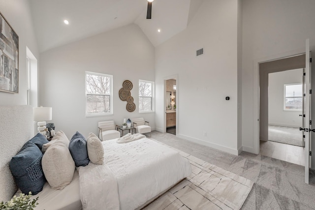 bedroom featuring ceiling fan, high vaulted ceiling, multiple windows, and ensuite bath