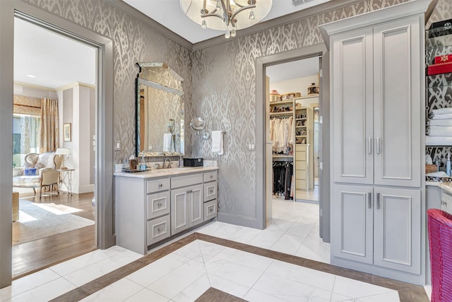 bathroom with ornamental molding, an inviting chandelier, and vanity