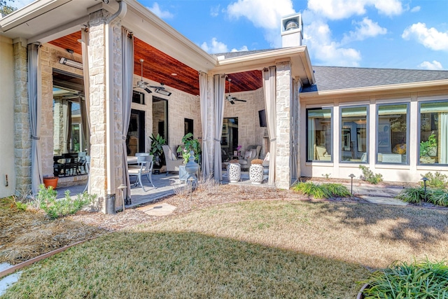 rear view of property with ceiling fan, a patio area, and a lawn