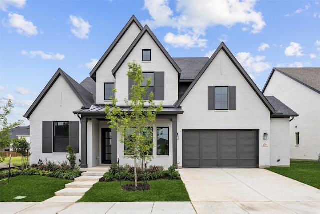 modern farmhouse with brick siding, a front lawn, an attached garage, and driveway