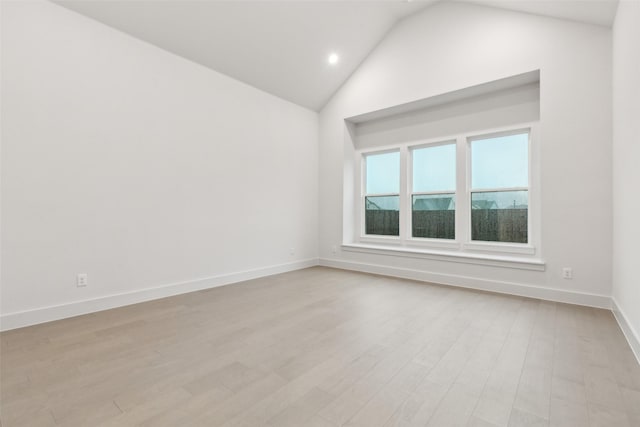 spare room featuring baseboards, recessed lighting, light wood-style floors, and high vaulted ceiling