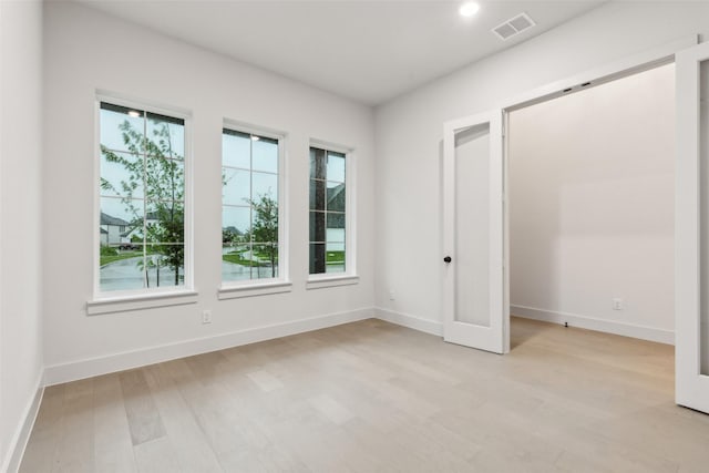 spare room with baseboards, visible vents, a healthy amount of sunlight, and light wood finished floors
