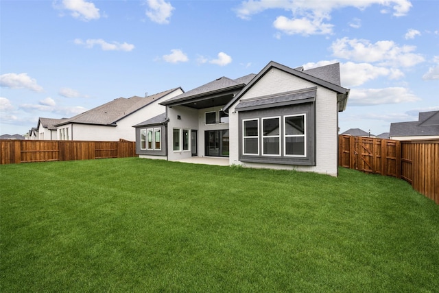 back of house with a lawn, brick siding, and a fenced backyard