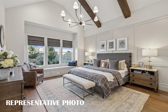 bedroom featuring wood-type flooring, a chandelier, and vaulted ceiling with beams