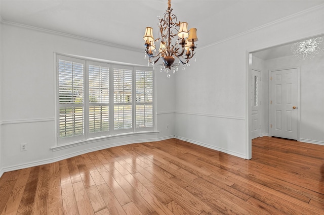 spare room with crown molding, an inviting chandelier, and hardwood / wood-style flooring