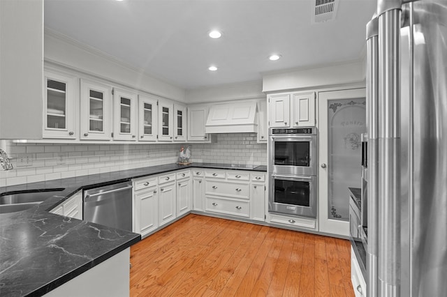 kitchen featuring custom exhaust hood, appliances with stainless steel finishes, sink, white cabinets, and backsplash