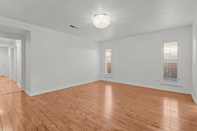 empty room with light hardwood / wood-style floors and plenty of natural light