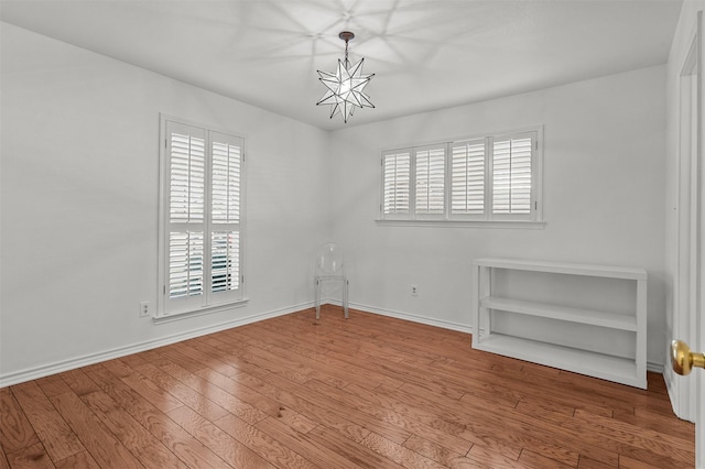 unfurnished room featuring hardwood / wood-style flooring, a healthy amount of sunlight, and a notable chandelier