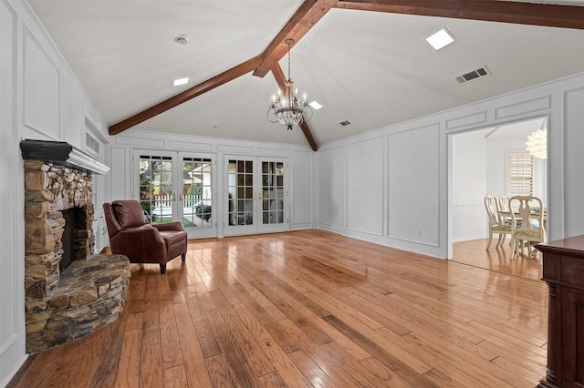 living room featuring light hardwood / wood-style floors, a chandelier, french doors, and vaulted ceiling with beams