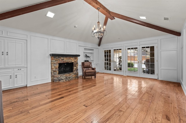 unfurnished living room featuring a stone fireplace, french doors, a chandelier, high vaulted ceiling, and beam ceiling