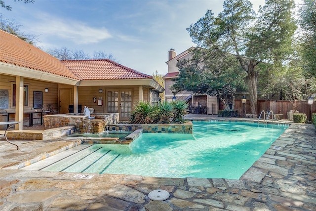 view of swimming pool with pool water feature, a patio area, and french doors