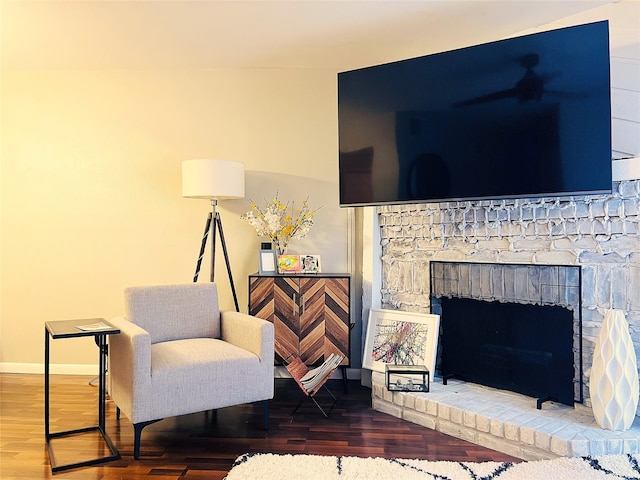 living area featuring a brick fireplace and wood-type flooring