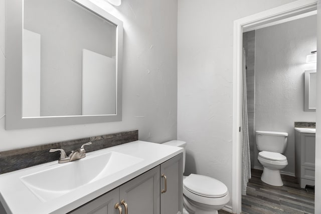 bathroom with hardwood / wood-style flooring, toilet, and vanity