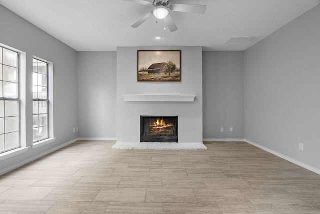 unfurnished living room featuring ceiling fan and a textured ceiling