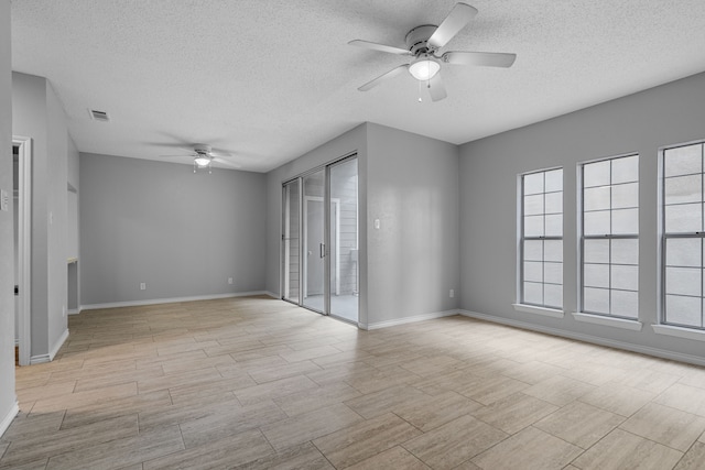 empty room with ceiling fan and a textured ceiling