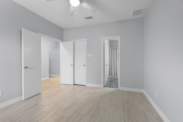 unfurnished bedroom with ceiling fan, connected bathroom, and a textured ceiling