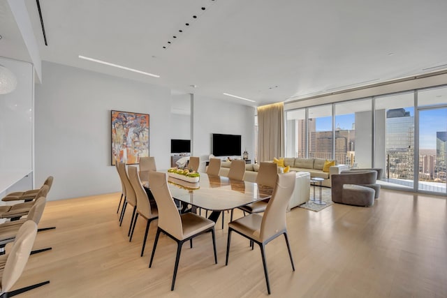 dining area with expansive windows and light hardwood / wood-style flooring