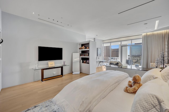 bedroom with expansive windows and light hardwood / wood-style floors