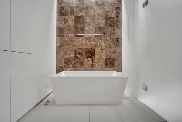 bathroom featuring tile patterned flooring, a tub to relax in, and tile walls