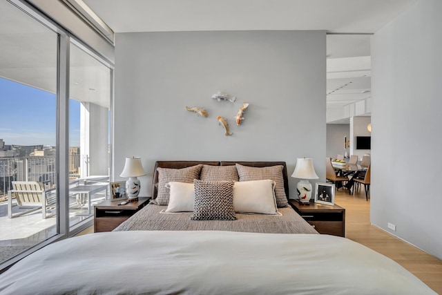 bedroom featuring a wall of windows, light hardwood / wood-style flooring, and access to outside