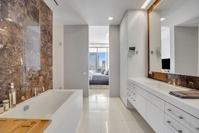 bathroom featuring vanity, tile patterned flooring, expansive windows, and a bathtub