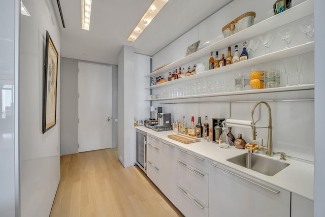 bar with wine cooler, sink, backsplash, white cabinets, and light hardwood / wood-style floors