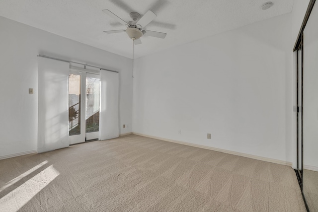 unfurnished room featuring ceiling fan, a textured ceiling, and light carpet