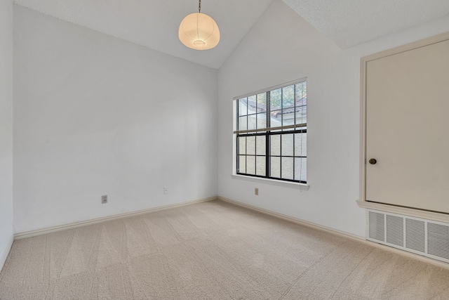 carpeted empty room featuring a textured ceiling and vaulted ceiling