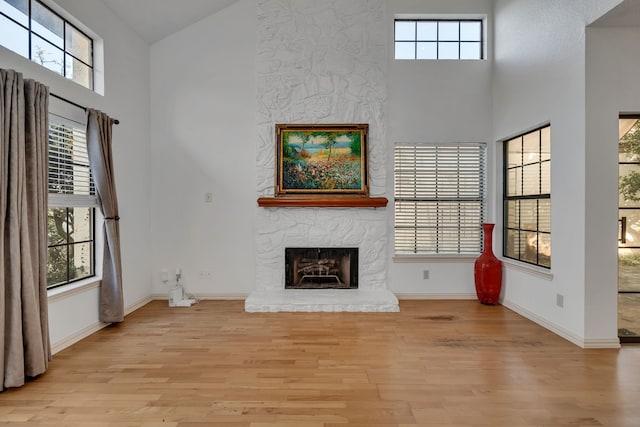 unfurnished living room featuring a high ceiling, light hardwood / wood-style flooring, and a fireplace