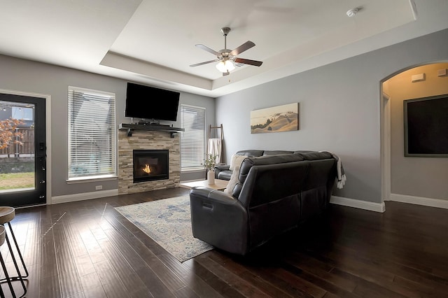 living room featuring ceiling fan, plenty of natural light, a tray ceiling, and dark hardwood / wood-style flooring