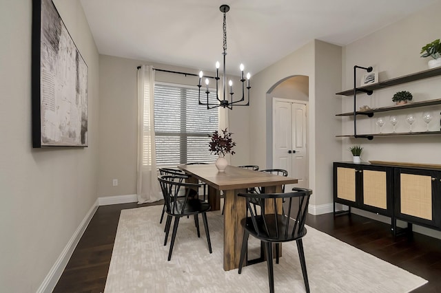 dining area featuring dark wood-type flooring, vaulted ceiling, and a notable chandelier